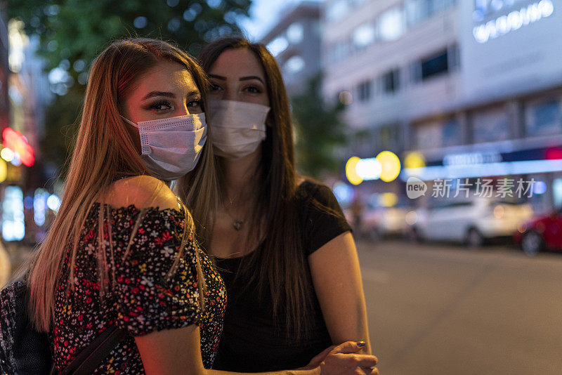 两名妇女晚上戴着医用口罩走在街上