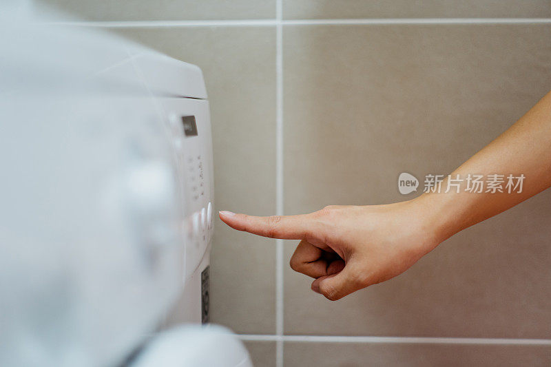 一个女人在按洗衣机上的按钮