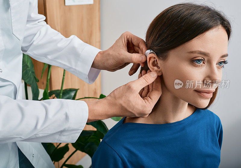 安装助听器在妇女的耳朵在听力诊所，特写，侧视图。耳聋治疗，听力解决方案