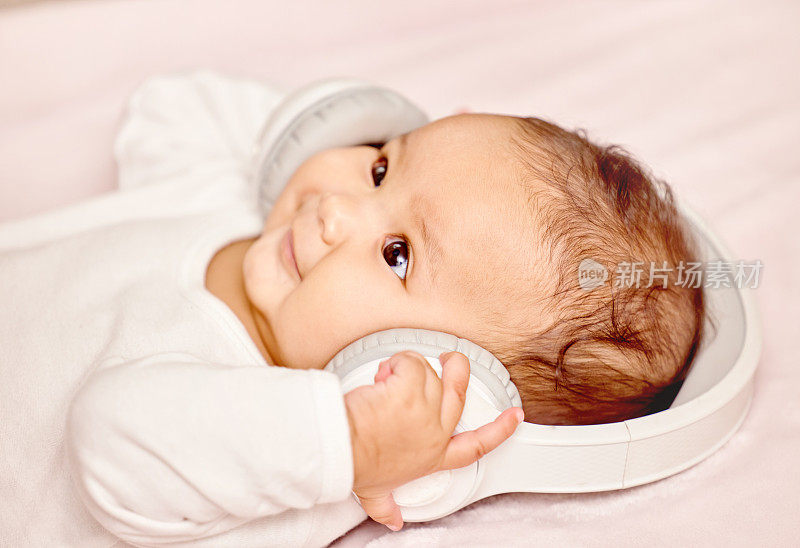 一张小婴儿戴着耳机躺着的照片