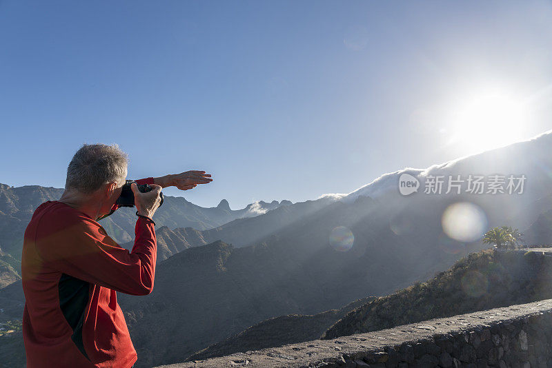 人们在拍摄加拉霍内山-拉戈梅拉山，背光与镜头光晕