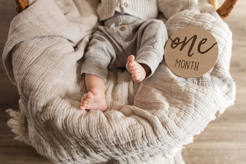一个月大的男孩的脚趾，有12个脚趾“多指”躺在一个舒适的薄纱棉毯子在摩西篮子里