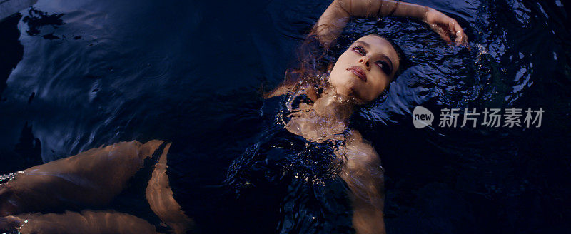 优雅的女人从水中浮现。用摄影机调情。奢华的美容护理隐喻