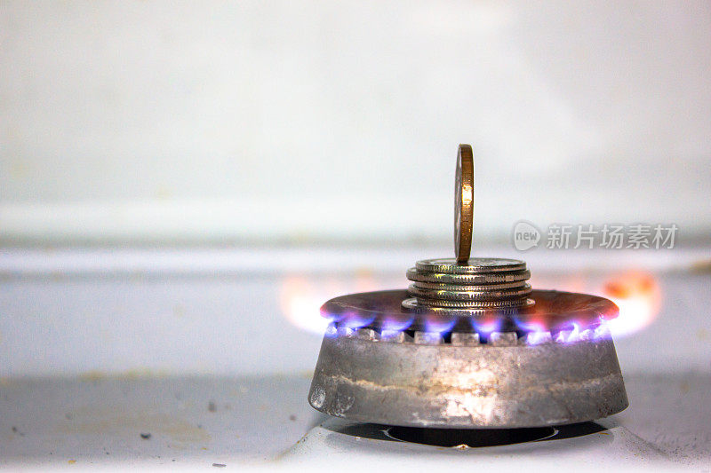 旧脏煤气灶上的硬币双燃烧器上的钱。丙烷火焰和金属货币。天然气成本概念。