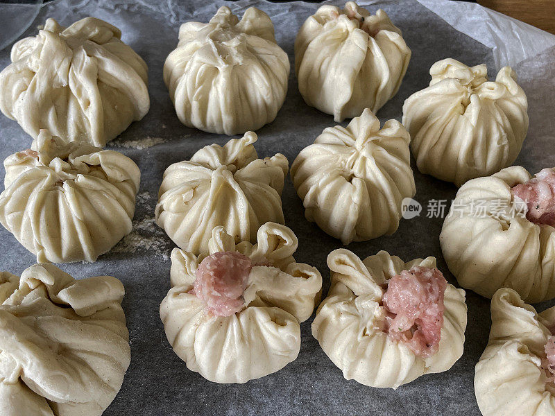 全框图像的防油羊皮纸覆盖着生的Momos(南亚饺子)，白面粉和水面团填充香肠肉准备在空气炸锅，高架视图