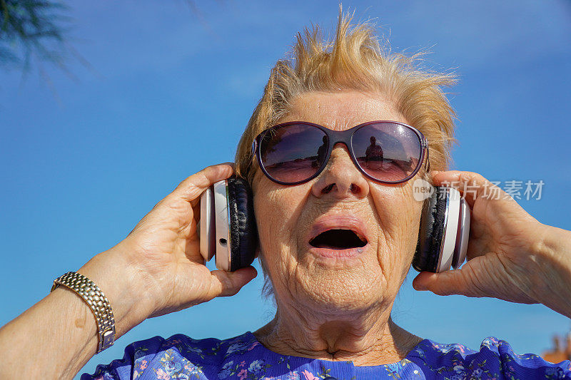 老妇人戴着耳机听音乐。神经系统发育