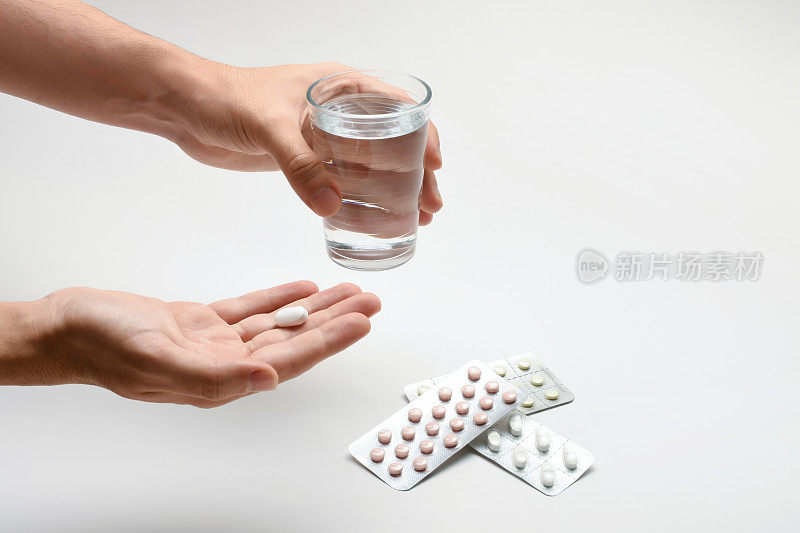 吃药、吃药，手里拿着一杯水和一粒药丸