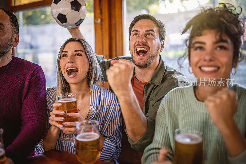 世界杯期间，快乐的体育迷在酒吧里看电视上的足球比赛。