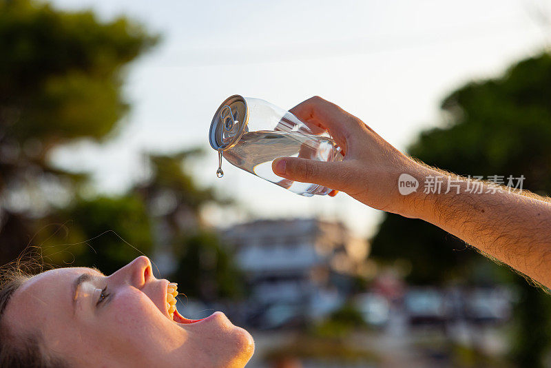 男人把塑料罐里的水倒进女人嘴里