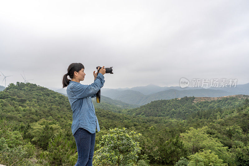 一位女摄影师在野外用相机拍照