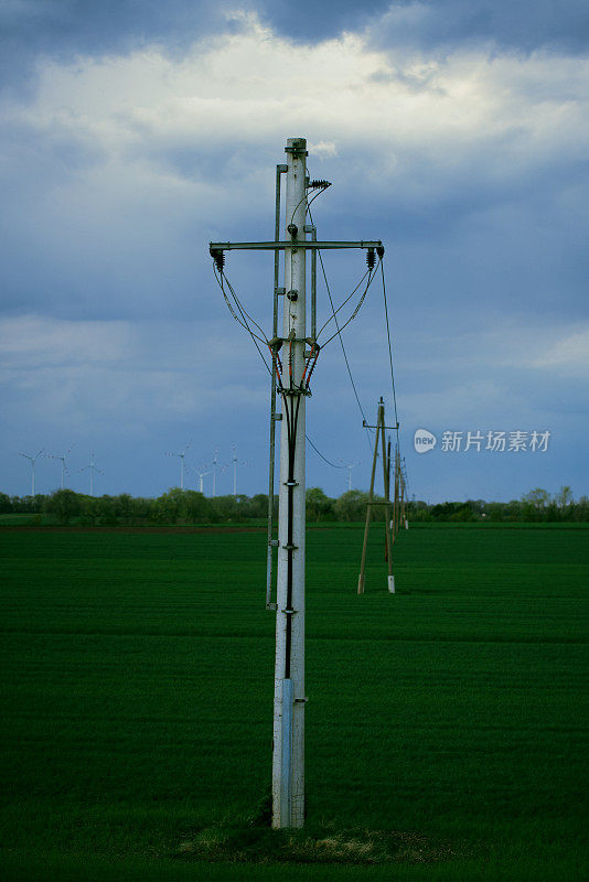电网穿越田野与多云的天空在奥地利