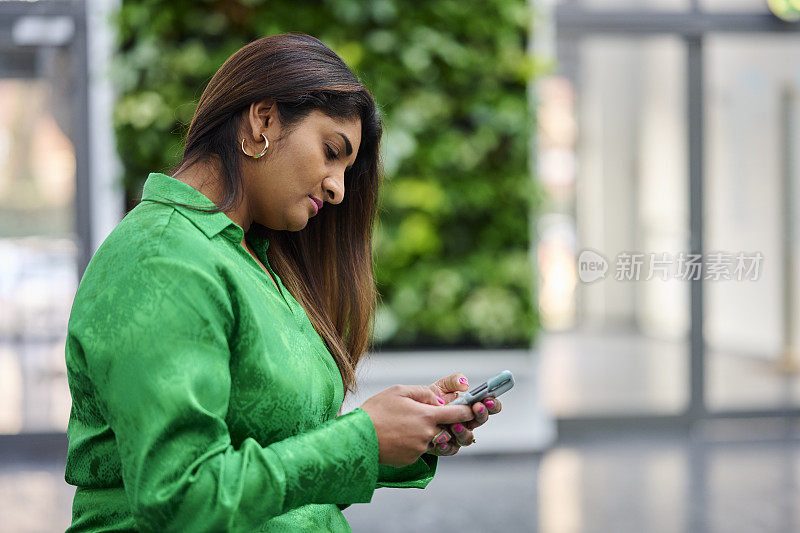 穿绿色衣服的女人检查移动设备