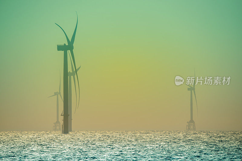 风力涡轮机的风扇在波光粼粼的海面上旋转。