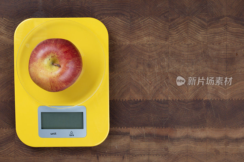 砧板上的厨房秤上有一个苹果