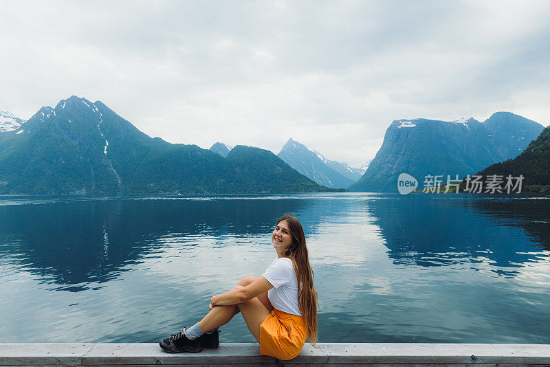 一个快乐的女人凝视着挪威峡湾的景色