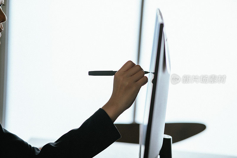 一个女人使用智能笔技术在数字显示器上工作和写作的特写，