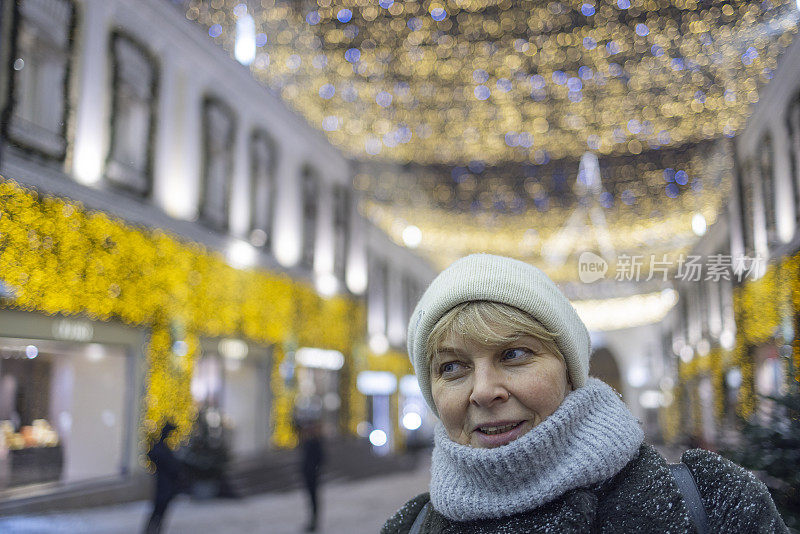 寒假假期。一名游客在圣诞节期间走在灯火通明的街道上，享受着为圣诞节和新年假期装饰起来的大城市。