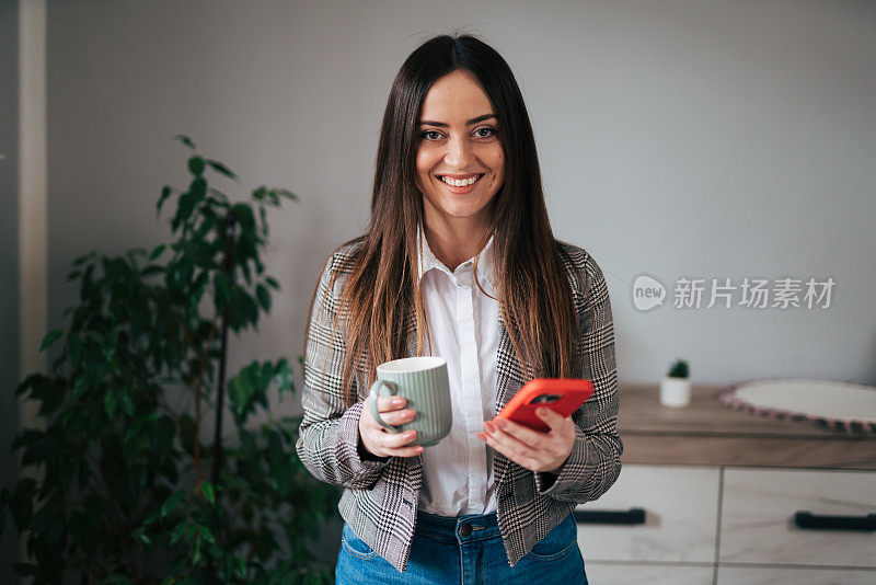 漂亮的女商人在家里的客厅边喝咖啡边打电话