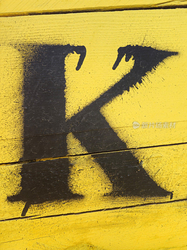 字母K画在黄色的木制背景上