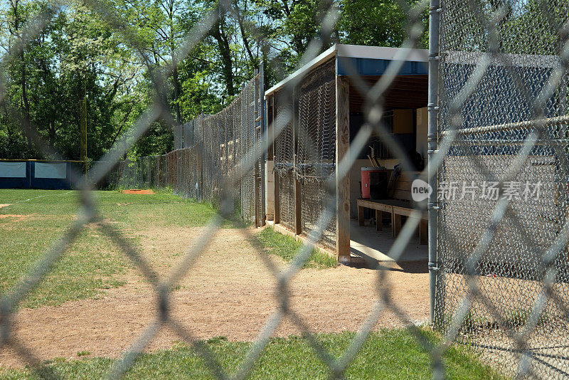 棒球一垒休息区和牛棚透过铁链围栏