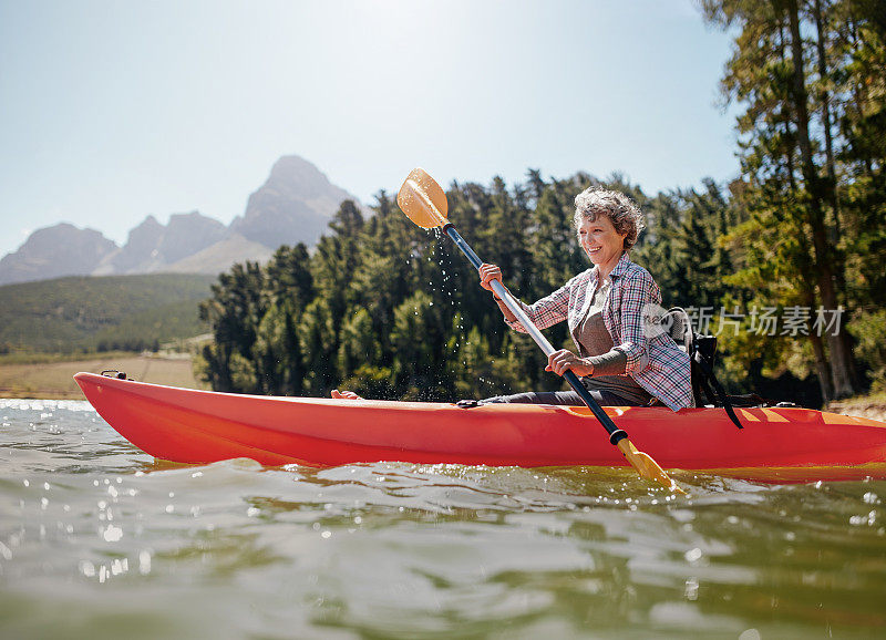 一个成熟的女人在湖中划着皮划艇