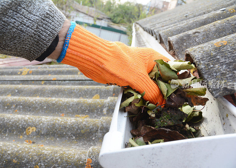 用手清理秋天的落叶。屋顶排水沟清洁技巧。在他们清理你的钱包之前清理你的排水沟。水槽清洗。