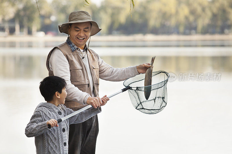 爷爷和孙子在湖里撒网捕鱼