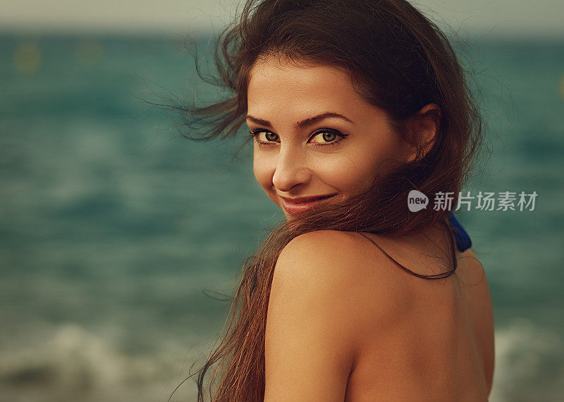 微笑的年轻女子看起来快乐的海洋背景。特写镜头