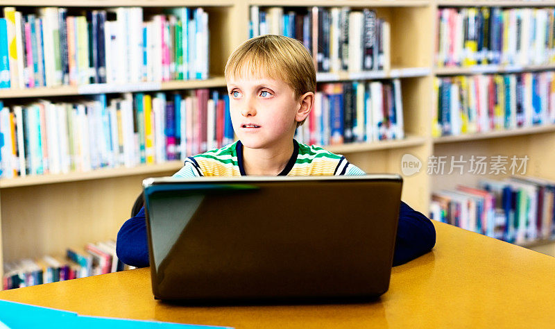 在图书馆拿着笔记本电脑的金发男生似乎心不在焉