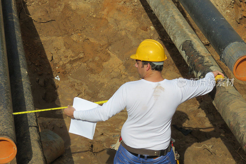 建筑工人测量两根管子之间的距离