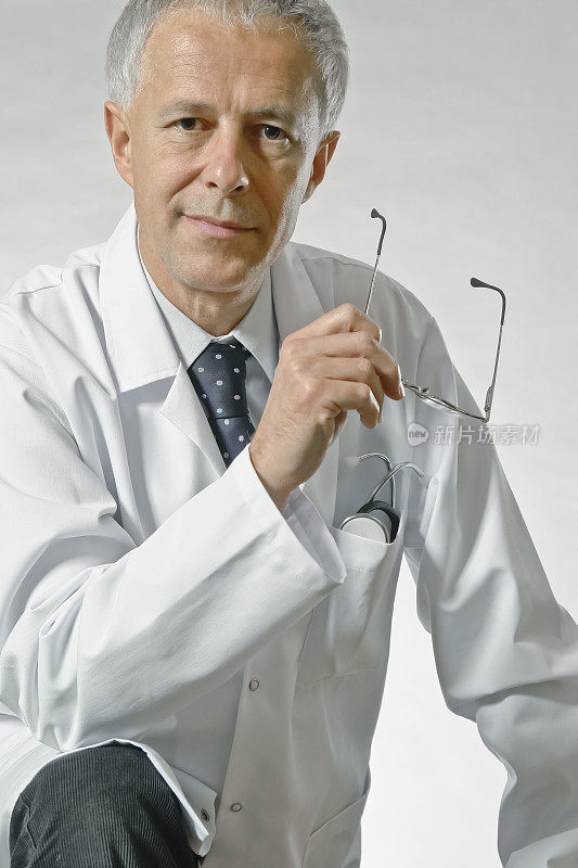 一个医生的肖像，手里拿着眼镜