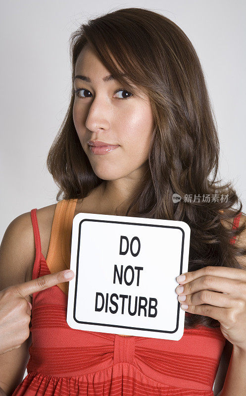 一位年轻迷人的西班牙女子举着“请勿打扰”的牌子