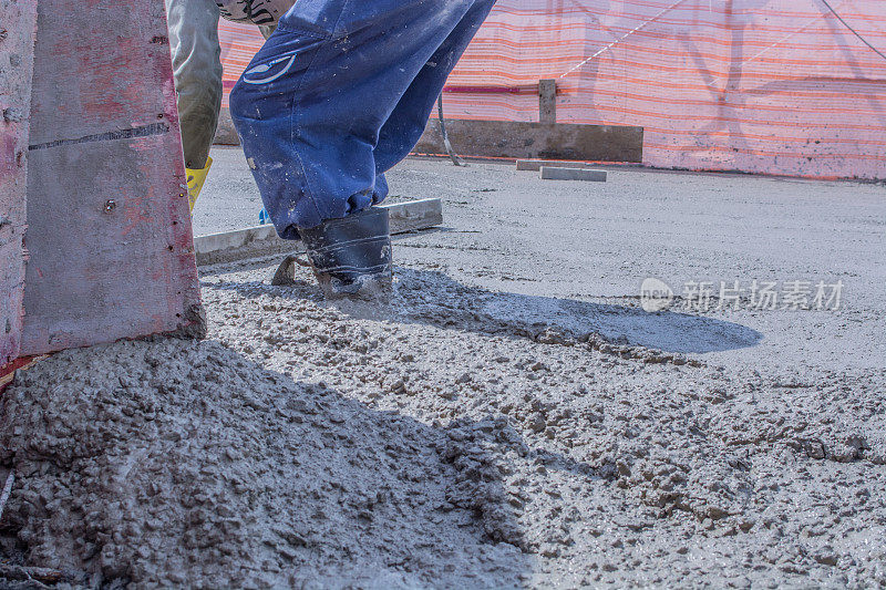 建筑工人压实液体水泥以加固混凝土地板