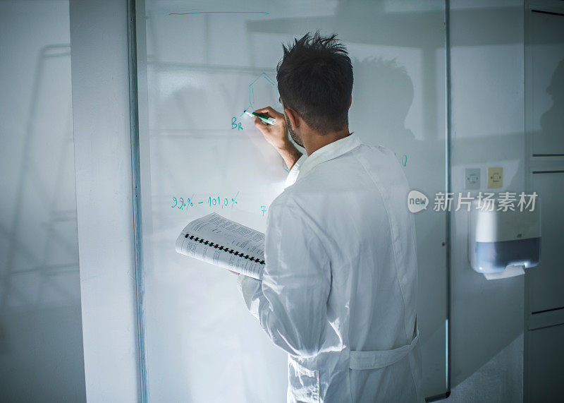 一个化学家在白板上写公式的后视图。