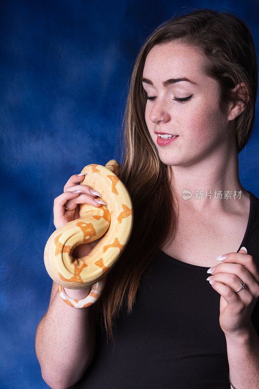 一个年轻女子抱着蛇看着蛇的彩色图像。