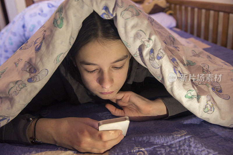青少年躺在床上，使用智能手机