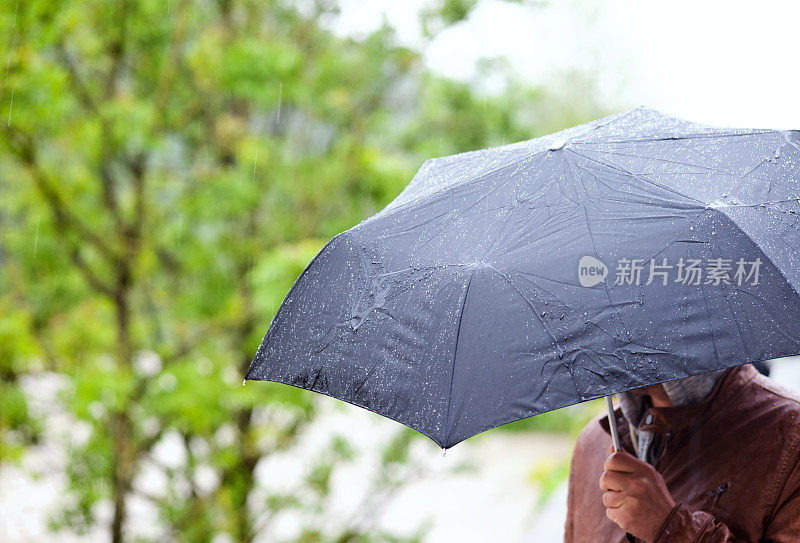 一个人撑着伞站在雨中