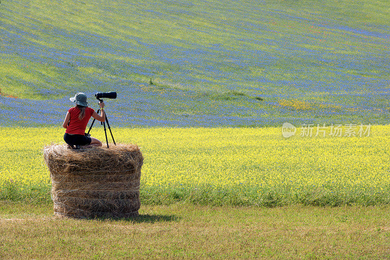 摄影师戴着帽子，穿着红衫，坐在贝尔上，Castelluccio，意大利