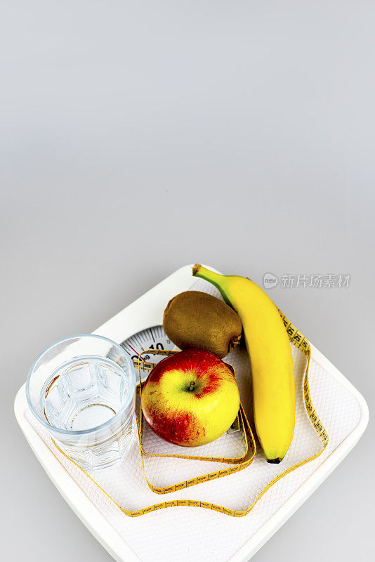 饮食的概念。苹果香蕉猕猴桃杯子水卷尺