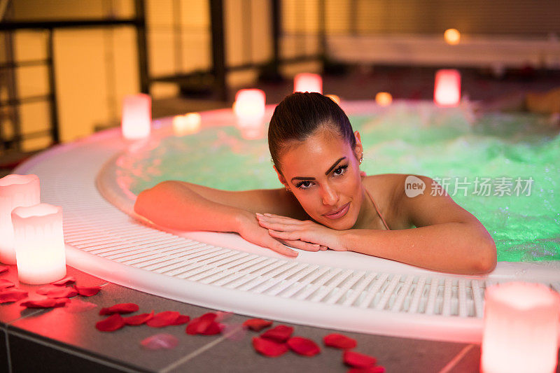 美丽的女人在健康水疗中心的热水浴缸中放松。