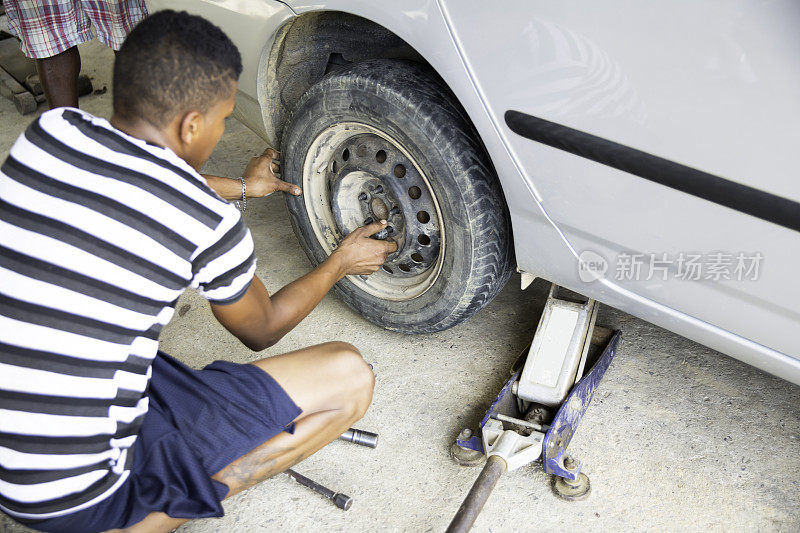 系列:年轻的洪都拉斯男子在罗阿坦的棚户区给轮胎换胎