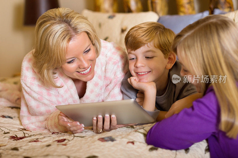 幸福家庭在床上使用数字平板电脑