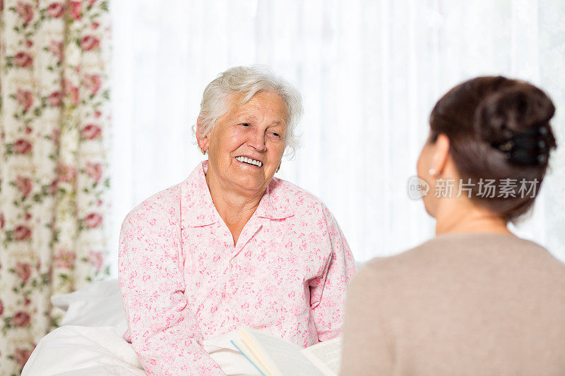 家庭护理员和老年妇女在家里的床上