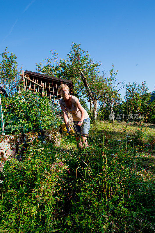 一个女人拿着除草机在山屋边上割草