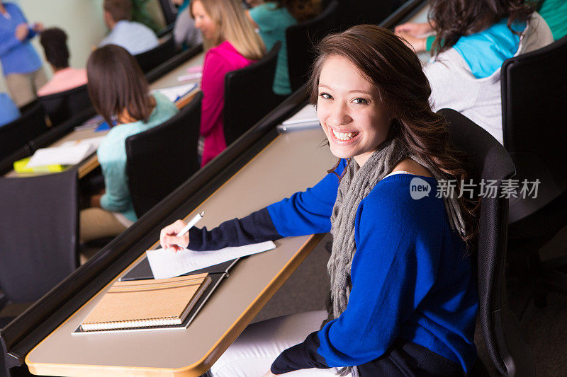 漂亮的女大学生在课堂上做笔记