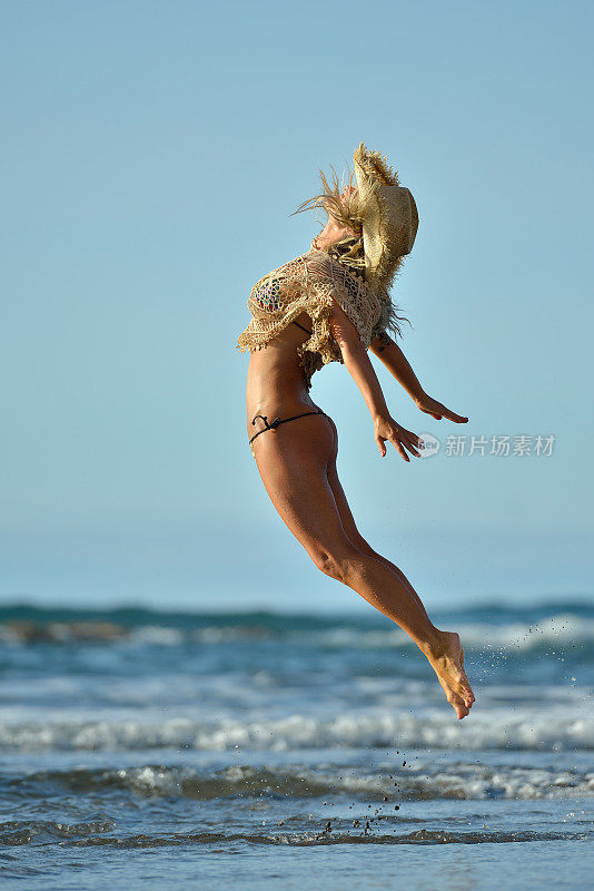 夏天，年轻女子在海滩上蹦蹦跳跳