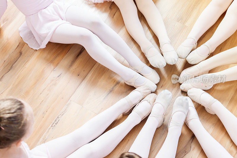 辨认不出的芭蕾舞者坐成一圈，他们的脚在一起