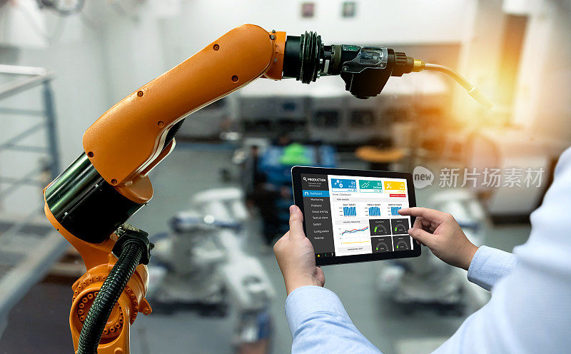 工程师手用平板，重型自动化机器人手臂机器在智能工厂工业用平板实时监控系统中的应用。工业第四物联网概念。