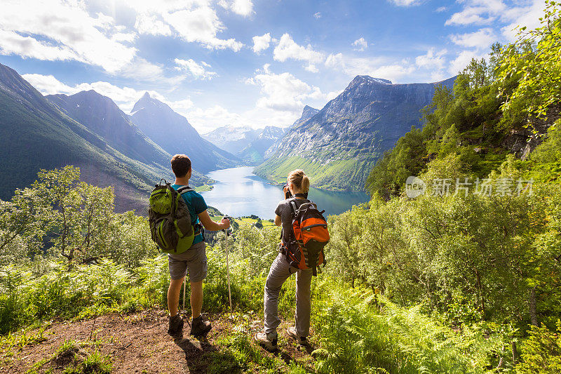 两个徒步者在有湖的山上看风景，阳光明媚的夏天