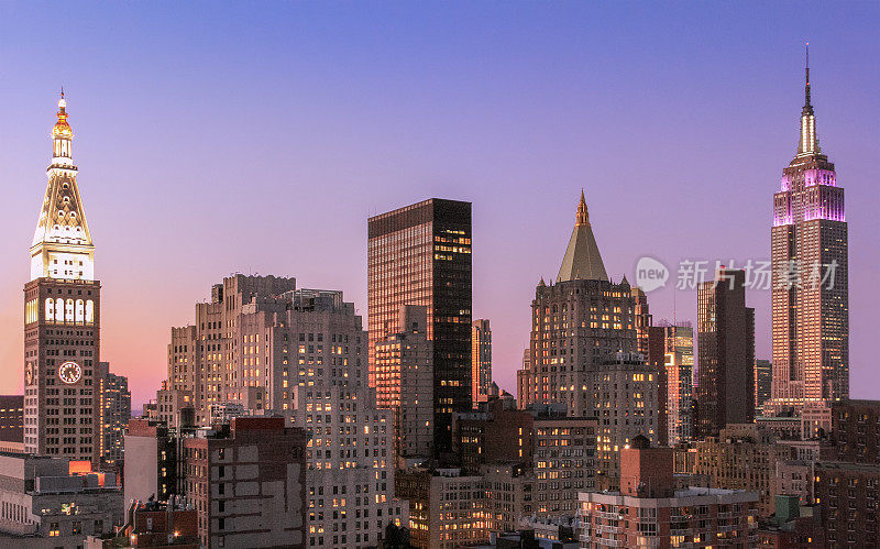 日落时的纽约城市天际线与帝国大厦、大都会人寿保险公司大厦、曼哈顿中城摩天大楼和橙蓝色晴朗的天空。